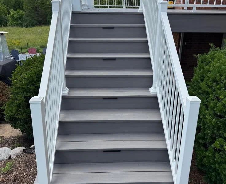 Gray composite stairs with white railings leading up to a second-story deck