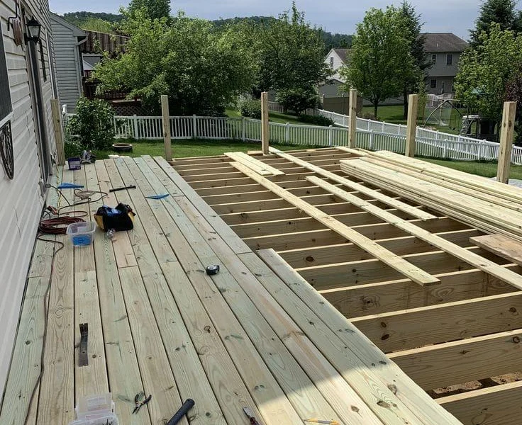 New pressure-treated joists and deck boards going in during a deck repair