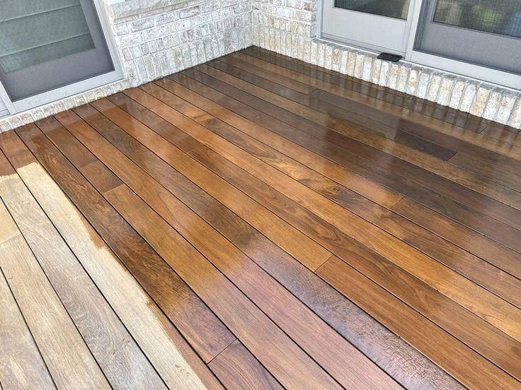 Deck boards halfway through staining, dark stain next to bare wood