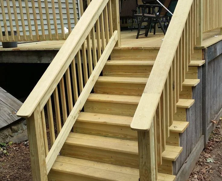 Pressure-treated wood stairs with railings leading up to a deck